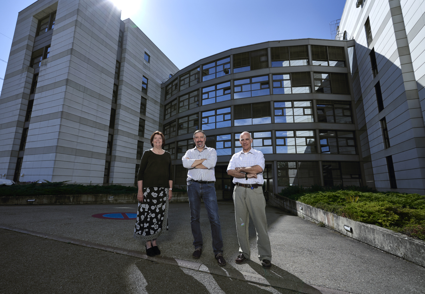 Three persons posing in front of a building