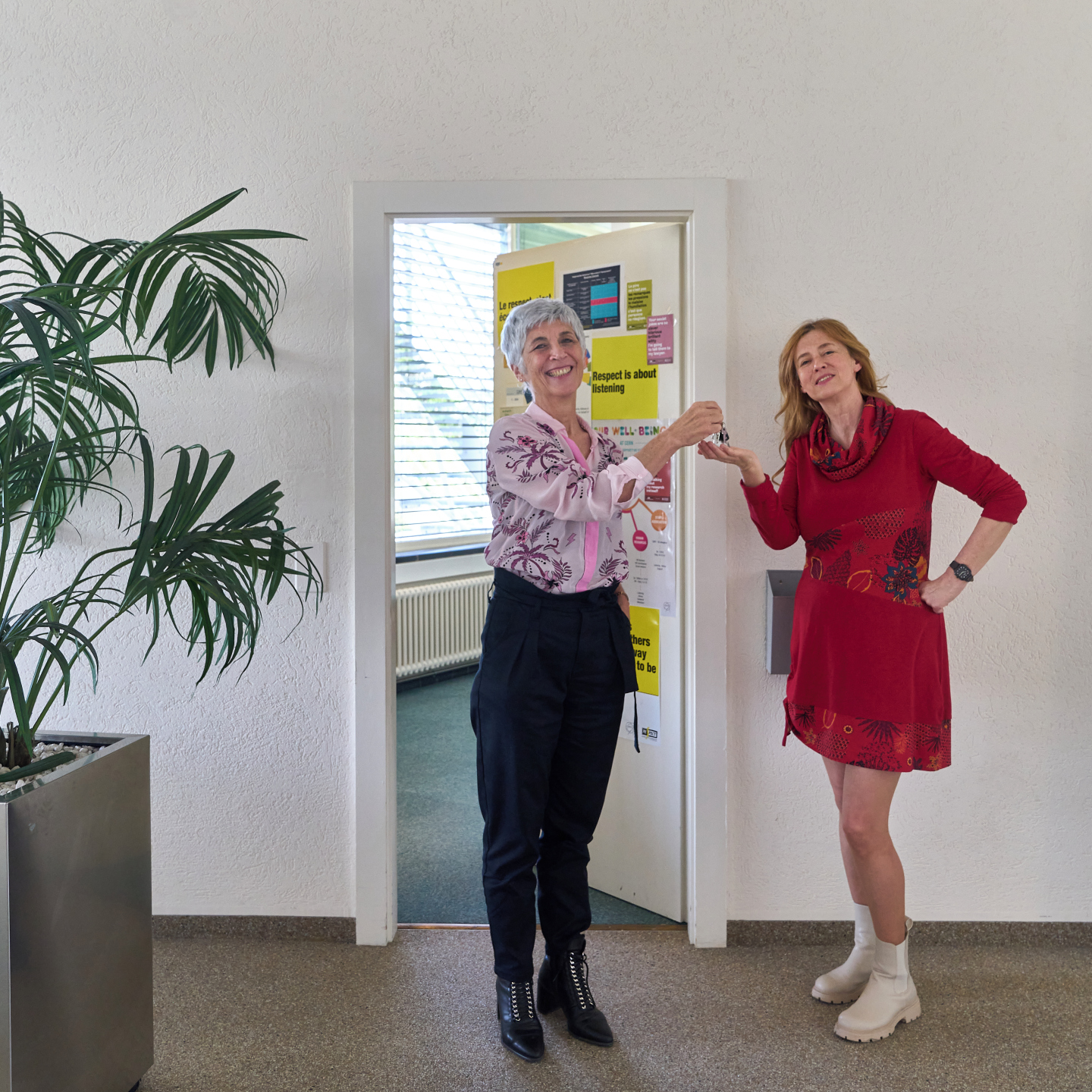 Laure Esteveny hands the keys to the Ombud’s office to Marie-Luce Falipou in front of the office's door.