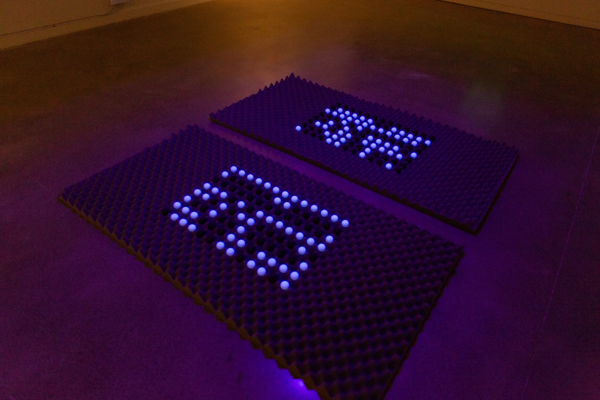 foam–UV-light installation showing "Hello, world!" written in binary