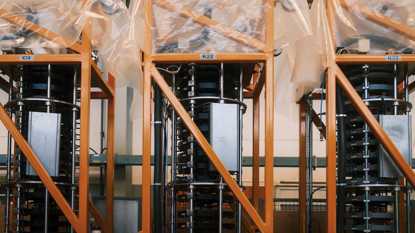 Three black notched cylinders inside an orange metallic structure