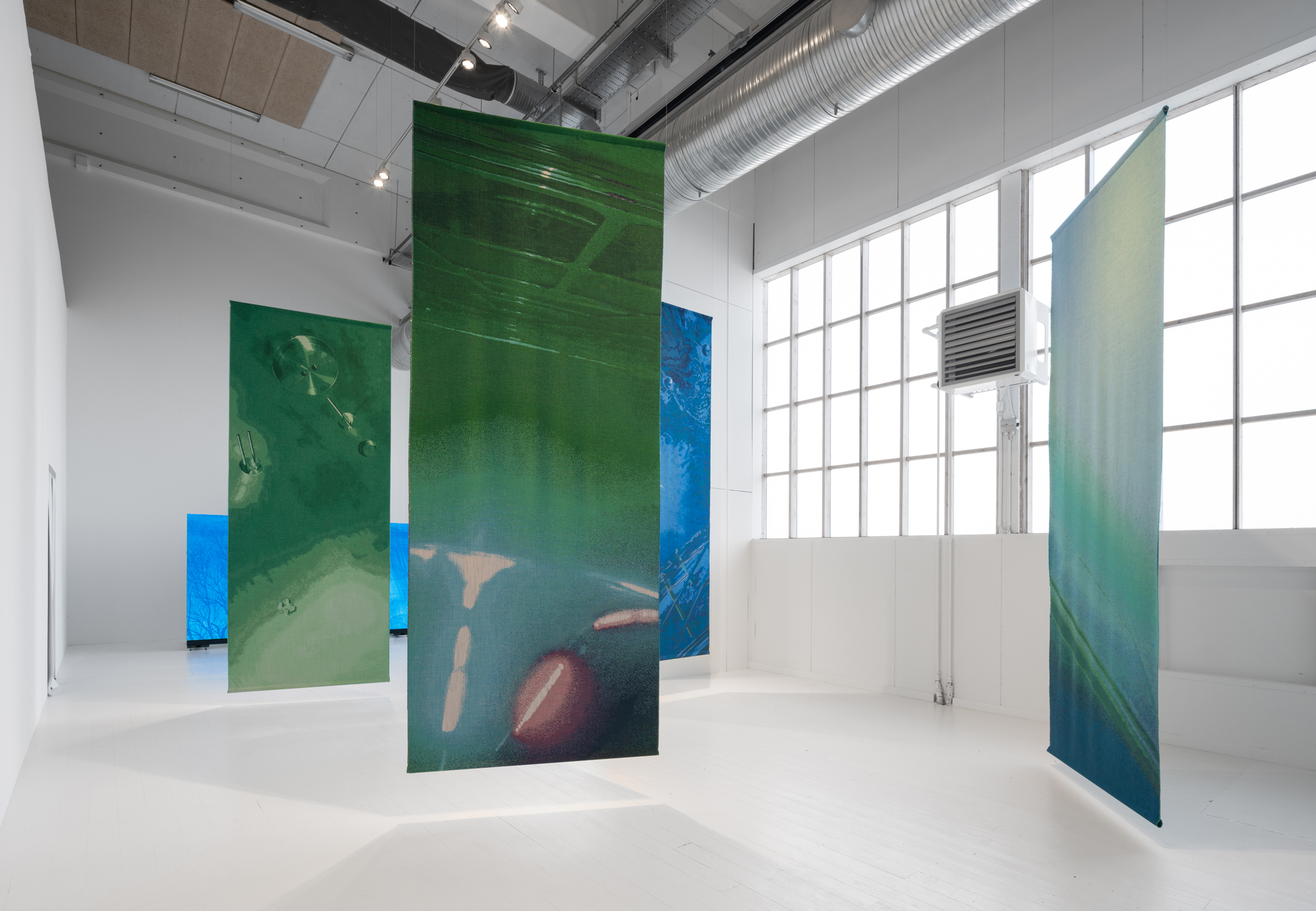Pictures are suspended from the ceiling in an industrial looking, white room