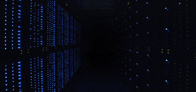 A dark room with flashing blue lights on either side from walls of data storage.