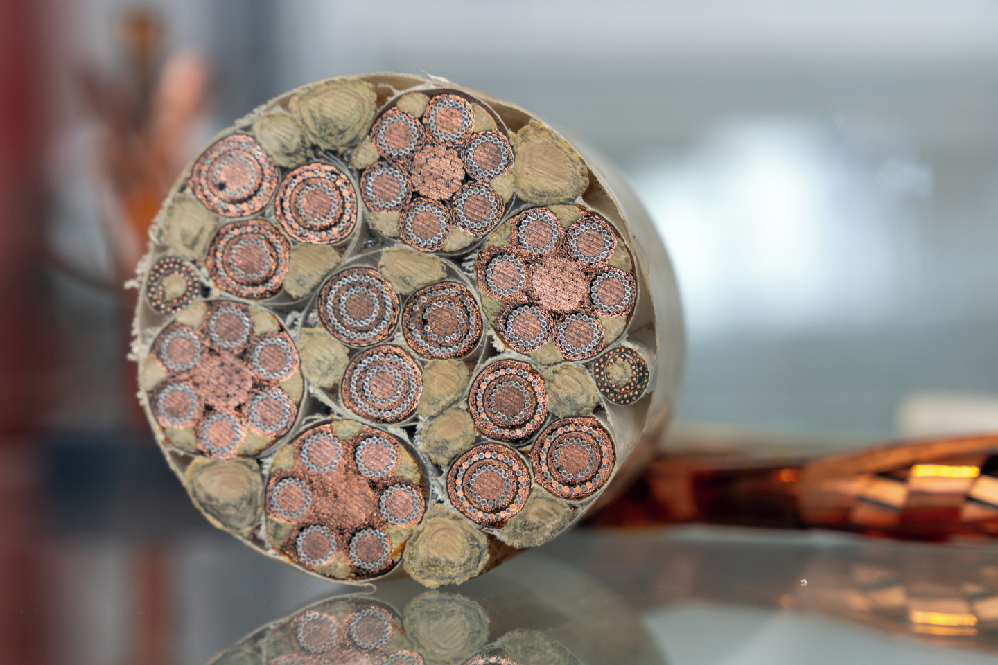 Cross-section of a cable which is made up of several nested circles of copper colour and with some mossy green insulating between them.