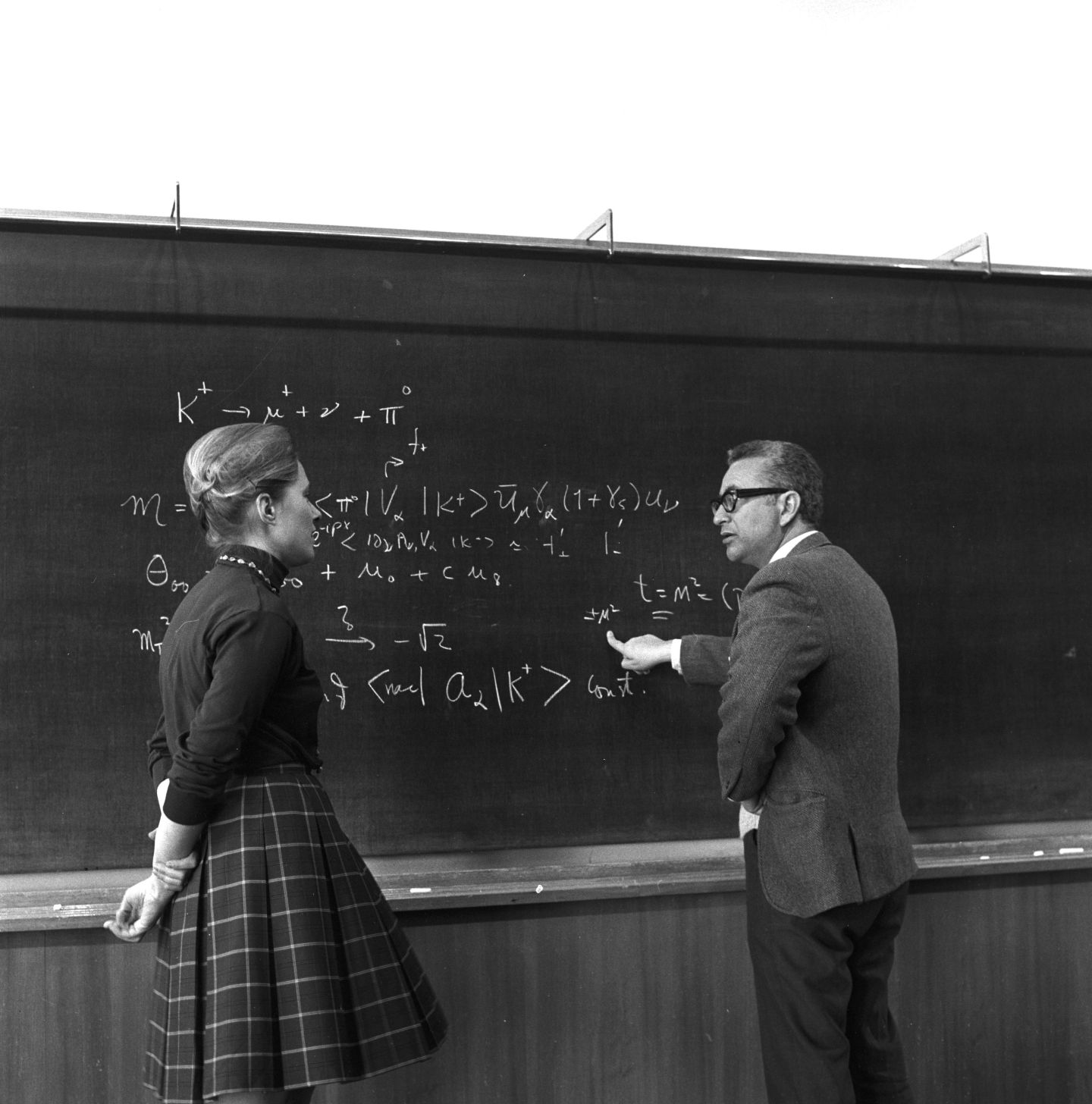 Woman and man talking by a blackboard of equations