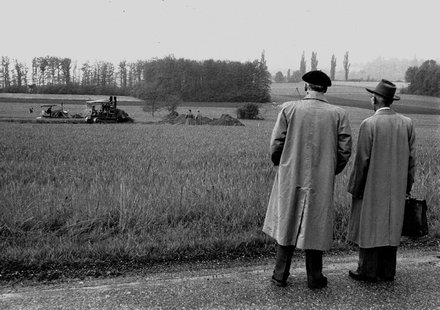 Two men looking out at a field where a worksite begins