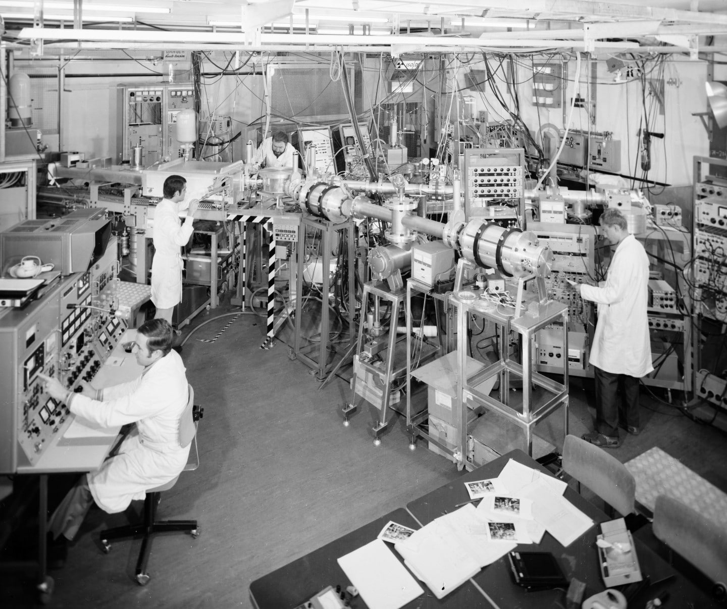 Personnes en blouse blanche entourées d'équipements dans un hall d'expérimentation