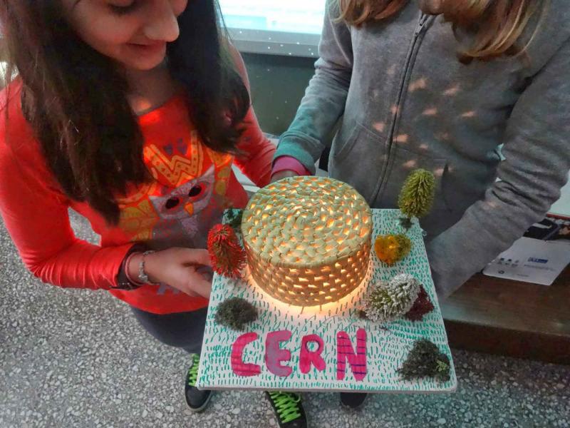 Students hold a model of the CERN Globe of Science and Innovation made from a basket and a light