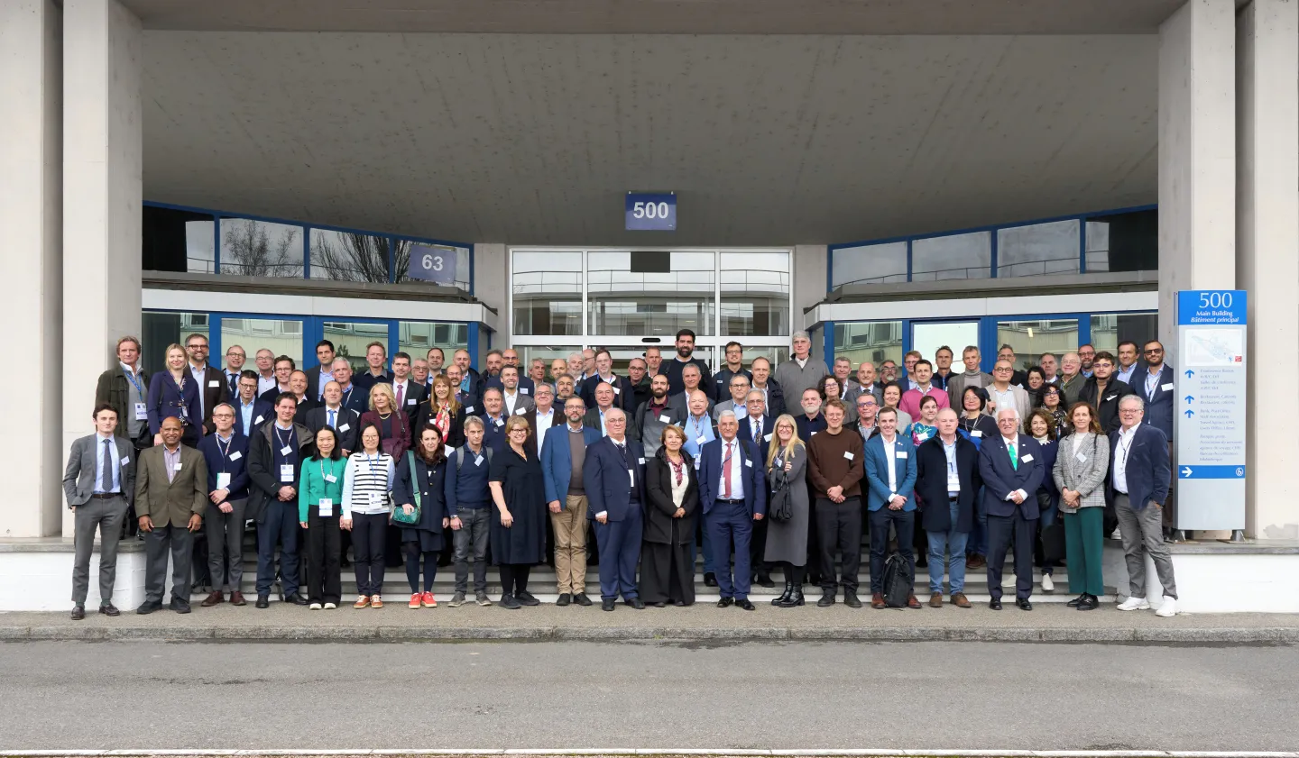 A large group of people stood at the entrance to a white building in three rows.