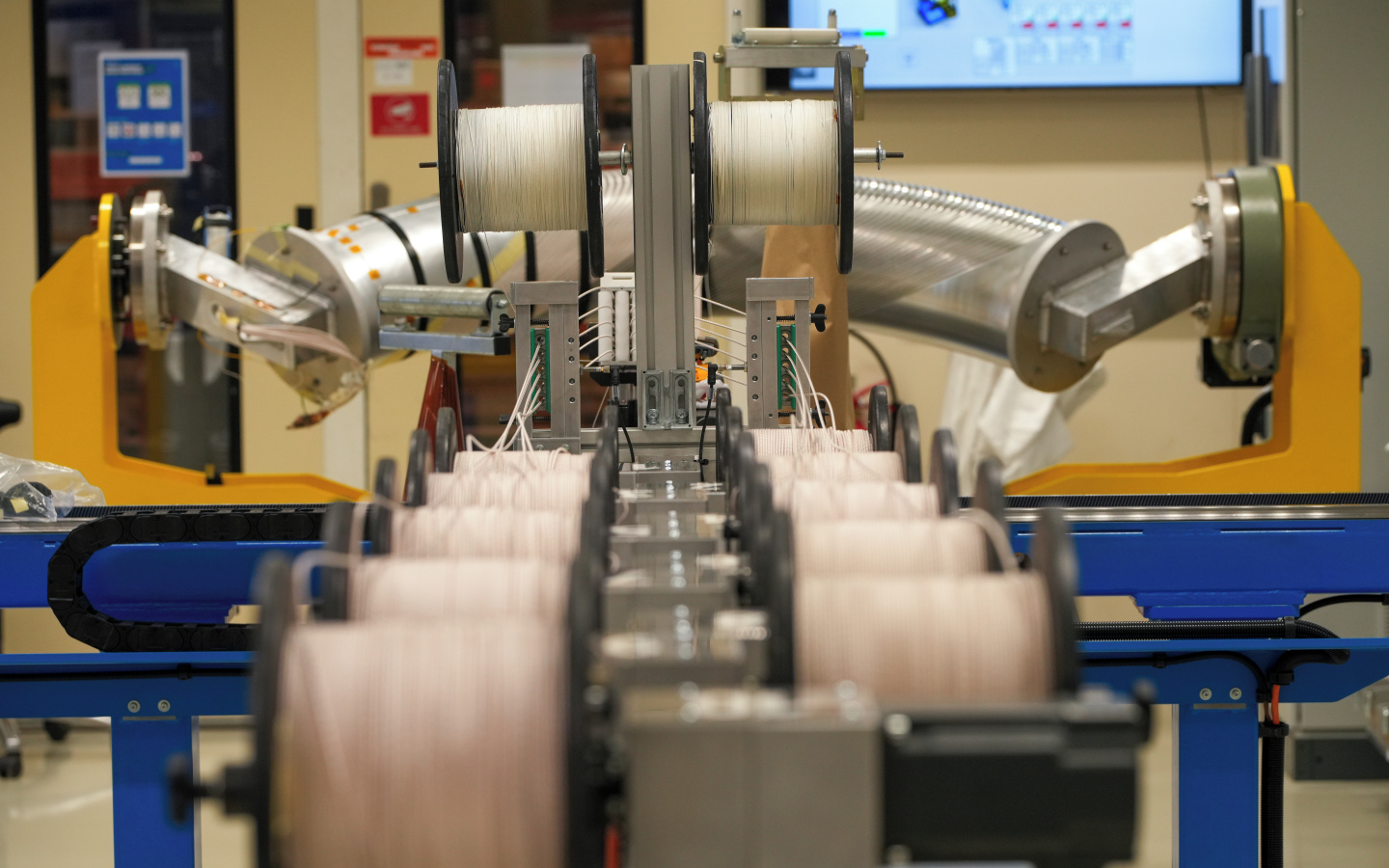 Vue du processus de fabrication des câbles. Les conducteurs passent par toute une chaîne de bobines avant d'être amenés dans un système de guidage qui permet d'obtenir un empilement régulier, avant la prochaine étape de fabrication