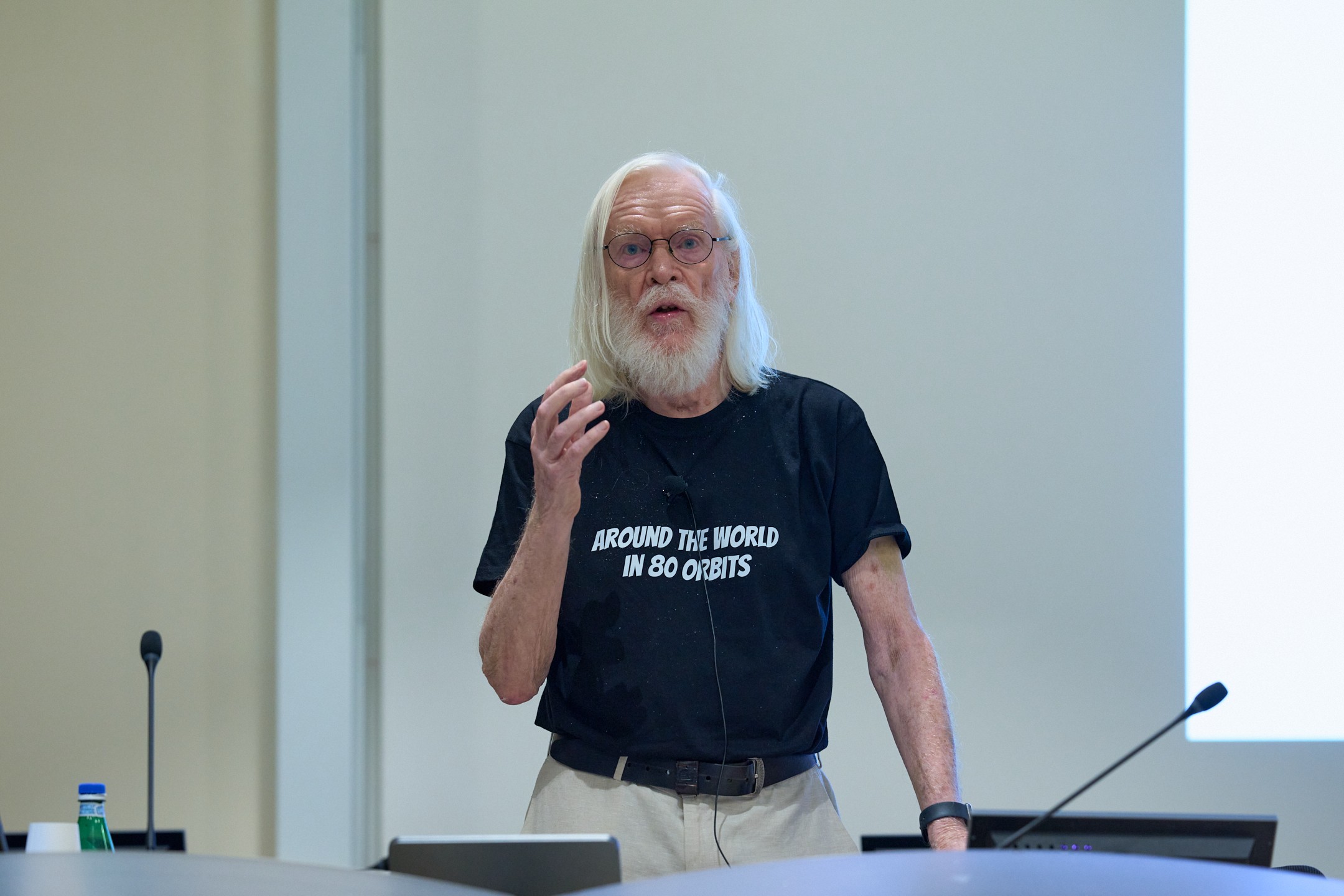 John Ellis wearing a black t-shirt reading "Around the world in 80 orbits"